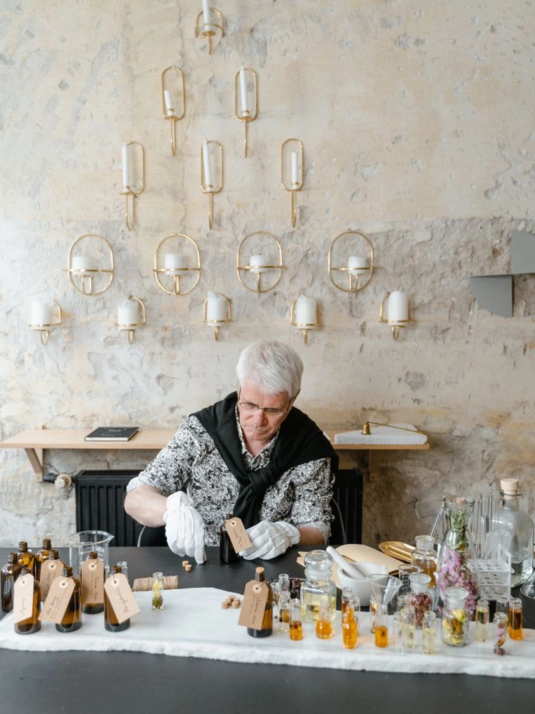 Parfumeur dans son atelier à Grasse, pesant des essences naturelles sur une balance ancienne